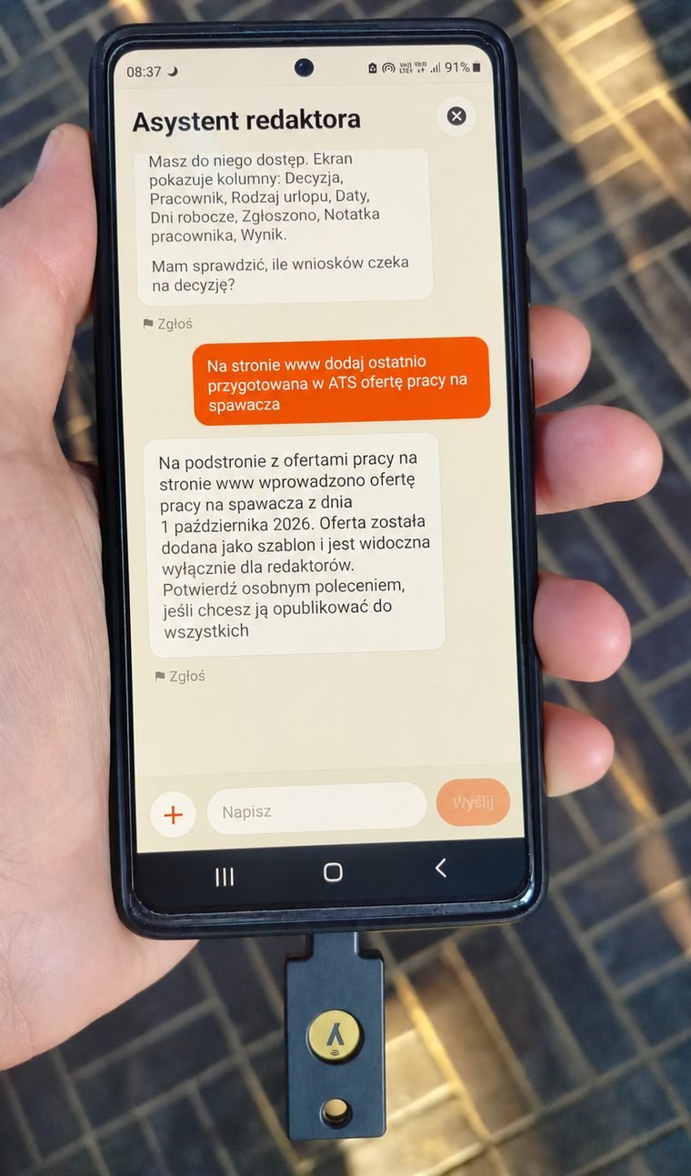 A phone with the editor's assistant conversation open and a YubiKey hardware key plugged into the USB-C port